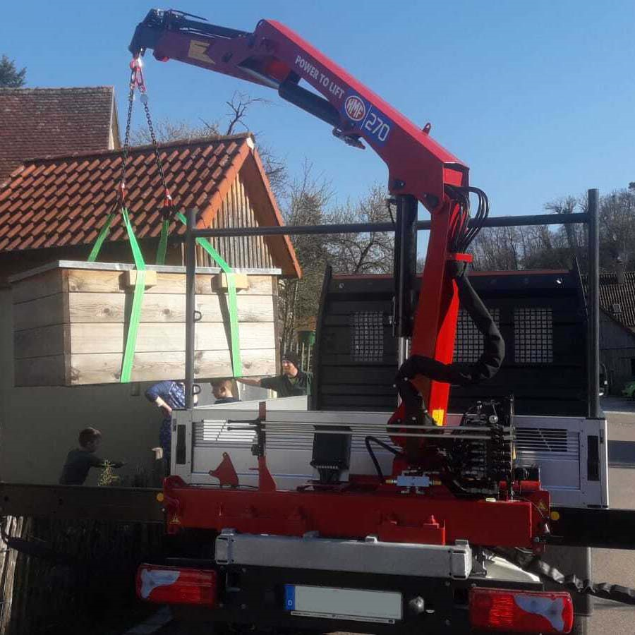 Petite grue montée sur camion soulevant du feutre de toiture enroulé